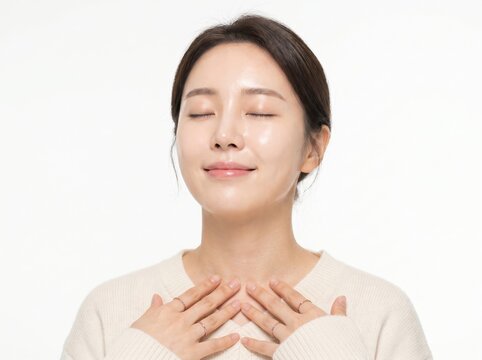 Serene Young Asian Woman with Closed Eyes and Hands on Chest Smiling for Wellness Concept