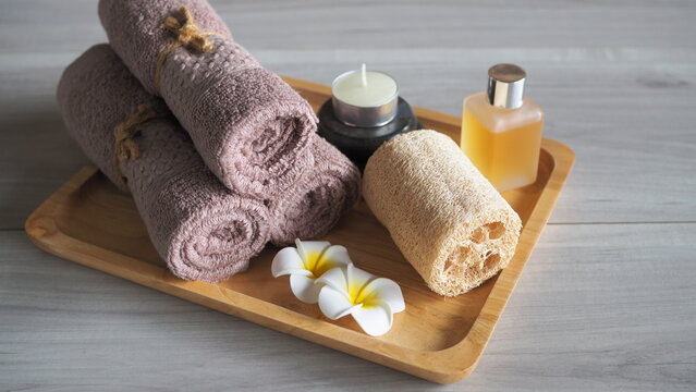 Minimalist flat lay coffee body scrub spa set with organic bath salt in a wooden bowl, a closed amber dropper bottle, cinnamon sticks, and neatly scattered roasted coffee beans. Top view on a warm rus