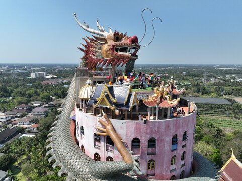 Aerial view of the iconic Wat Sampran Dragon Temple, featuring a massive dragon sculpture coiled around a pink building in Khlong Mai, Nakhon Pathom, Thailand.