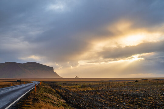 Dramatic sunset rays filtering through rainy clouds over Iceland landscape