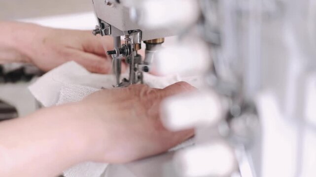 Closeup of a person sewing white fabric with a sewing machine
