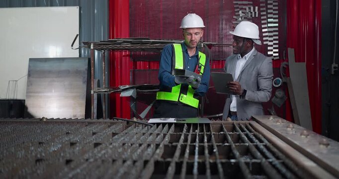 Sales engineer briefs a client in a metal workshop, using sample parts and technical references to present fabrication capabilities, customization options and production solutions.
