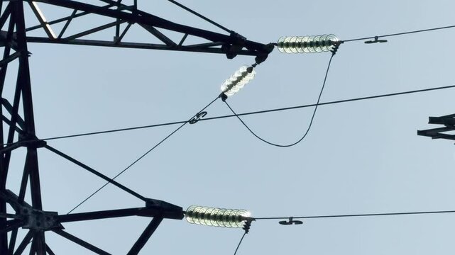 A close-up view shows the detailed metal frame and glass insulators of a power tower. This complex electrical structure evokes a strong feeling of modern power and technological wonder.