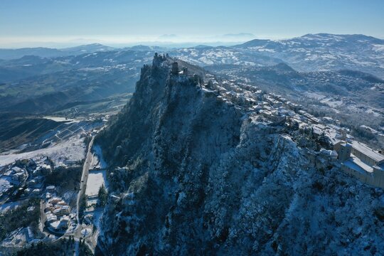 Aerial view of Guaita Tower perched on the snowy cliffs of Mount Titano with historic stone fortifications and winter landscape in Citta di San Marino, San Marino, San Marino.