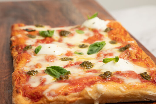Pizza rectangulaire avec sauce tomate et fromage sur une planche en bois