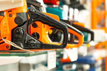 Fototapeta premium A Variety of Electric Chainsaws Displayed on Shelves in a Tool Store, Showcasing Their Unique Designs and Features for Wood Cutting Enthusiasts and Professionals