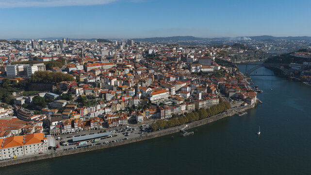 Aerial view of the historic city of Porto along the Douro River, featuring dense terracotta rooftops, traditional architecture, and the Dom Luis I Bridge, Porto, Porto District, Portugal.
