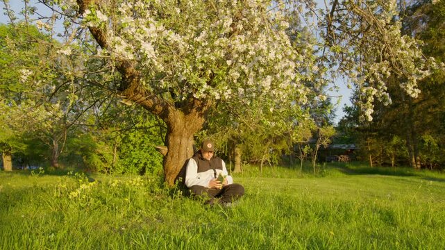 A man reading a comic under a tree