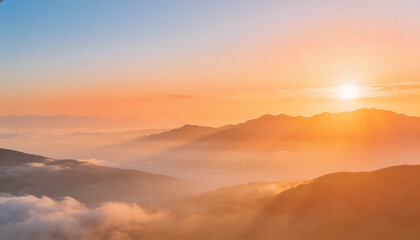 Naklejka premium Golden sunrise illuminating misty mountain ranges with warm morning light and clouds, creating a peaceful panoramic natural landscape.