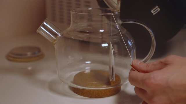 Pouring Hot Water Into Glass Teapot With Tea Bag