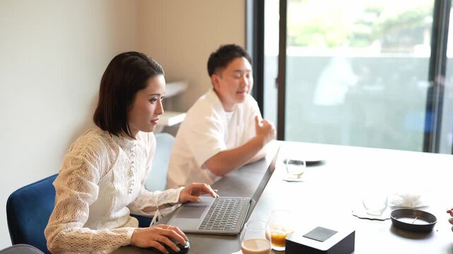 Woman types on laptop, man watches closely. Soft lighting, quiet office space. Focused, collaborative energy between two professionals. Ideal for business meetings, teamwork concepts
