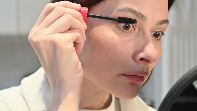 Girl applying mascara to eyelashes at home