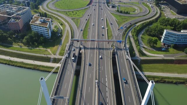 Aerial top-down drone view of Danube bridge, riverfront bike path and highway interchange in Linz, Austria