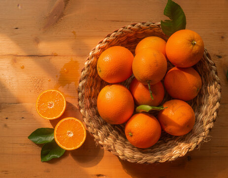 Fresh oranges in a woven basket on a rustic wooden table