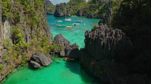 Aerial Forward Shot Flying From Small Lagoon to Entrance in El Nido, Philippines. Drone View Navigating Through Narrow Limestone Cliff Opening Toward Open Ocean Water.