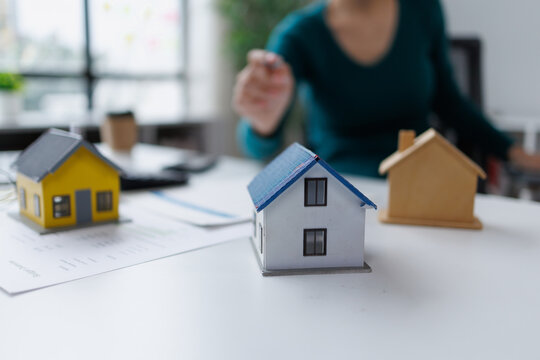 Agent presenting house models and property documents, advising on real estate investment options, making a decision on home ownership or rental