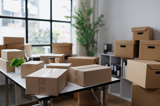 Cardboard shipping boxes and moving cartons filling an office or home space, symbolizing e-commerce, logistics, relocation, storage, delivery, and distribution services