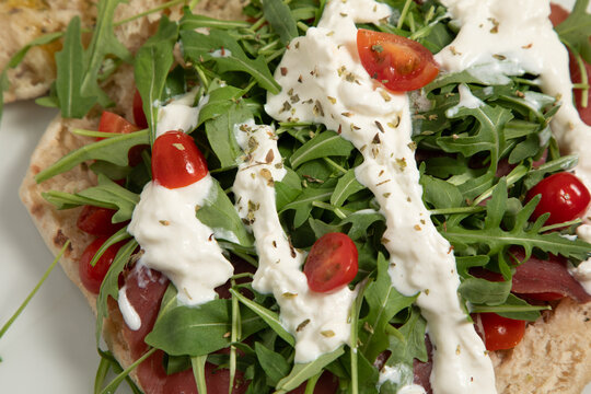Pr&eacute;paration d'une focaccia garnie de roquette et de tomates cerises