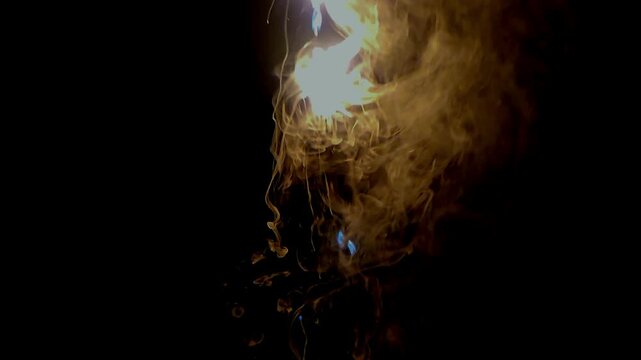 Abstract close-up footage of blue flames and swirling smoke rising from burning plastic against a deep black background. The flowing smoke creates dramatic organic patterns