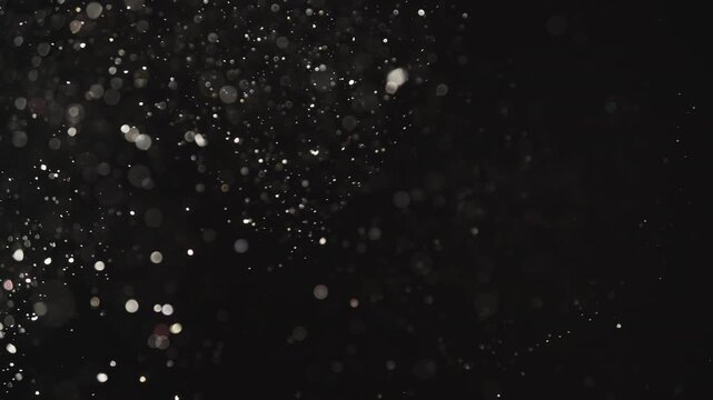 Slow motion real dust particles floating mid air over dark background