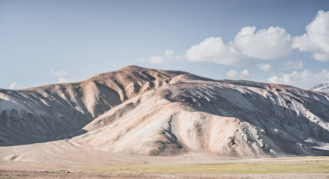 A mountain landscape featuring rocky peaks and snow-capped glaciers, with a valley containing fields, pastures of fresh green grass, and clear-water rivers&mdash;suitable for a background image