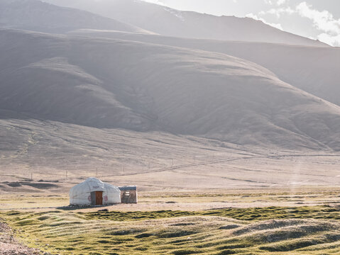 Yurt in a Tian Shan mountain valley set against a rocky slope at sunset; a traditional dwelling of the local Pamir people