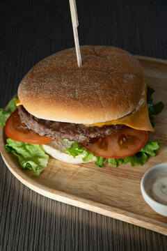 Burger avec salade, tomate et fromage sur une planche en bois