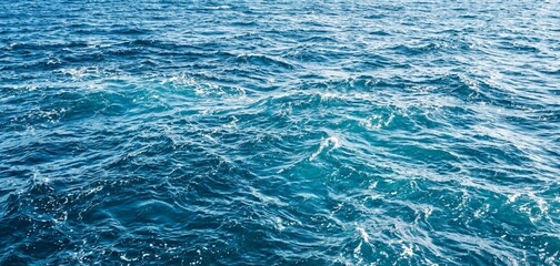 Obraz premium Dynamic blue ocean surface with shimmering sunlight creating a vibrant texture of rippling water, perfect for background or tranquil marine themes