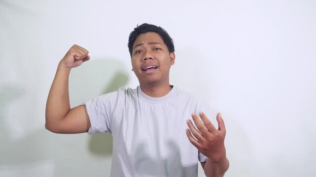 man flexing bicep in white shirt in studio.