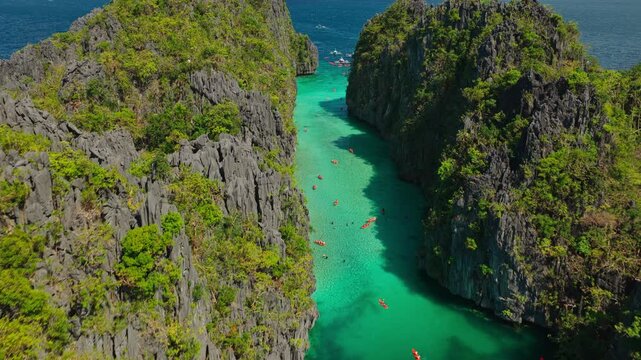 Aerial Fast Forward Tracking Shot Up Big Lagoon Entrance in El Nido, Philippines. Drone View Flying Quickly Through Shallow Turquoise Channel Framed by Limestone Cliffs.