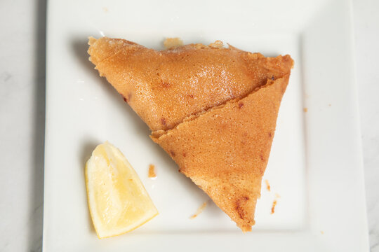 Samoussek avec un morceau de citron sur une assiette blanche