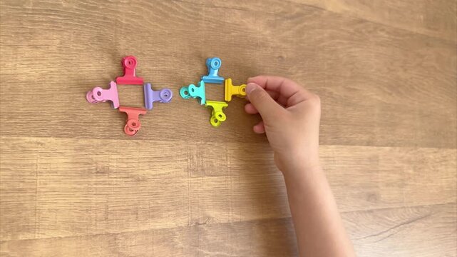 Child Hand Places the Eighth Colorful Ring Clip to Complete a Cross Pattern, 4K