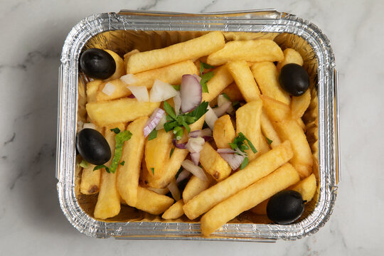 Frites avec oignons et olives servies dans une barquette
