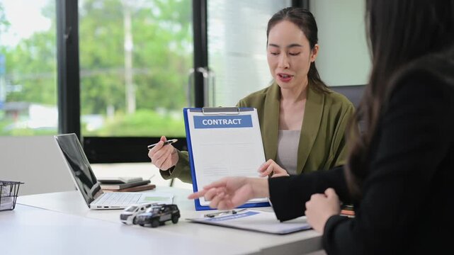 Professional women discuss auto insurance and car loan options using model cars in a modern office. and automotive commercial themes.