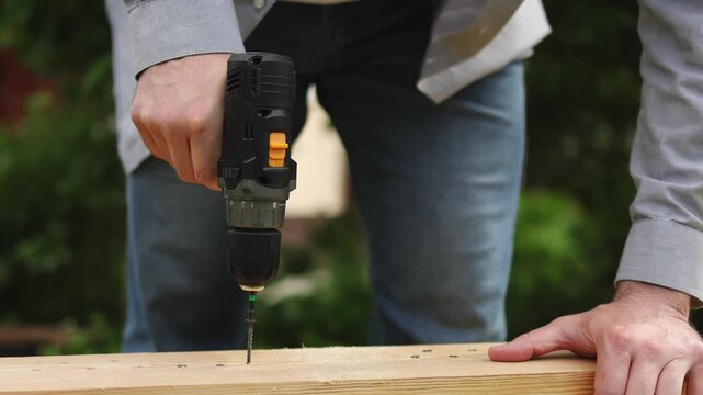 A man uses a screwdriver. Wooden board. Self-tapping screw. Slow motion video. High quality 4k footage