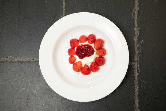 Dessert avec des fraises et de la confiture au centre sur une assiette blanche