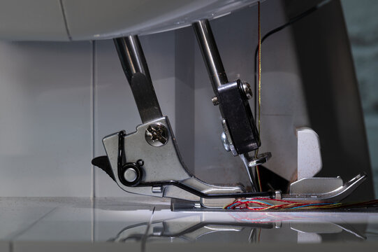 Overlock sewing machine foot with two needles at the bottom and carrier in close-up from the left side
