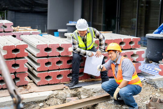 A field worker consulting with a site engineer about the foundation work.A construction worker on the ground points out a specific detail,seeking clarification from the project manager.