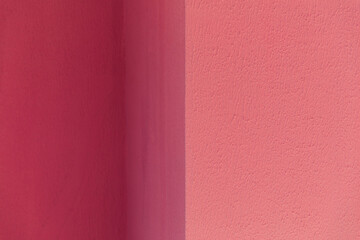 Fototapeta premium A textured wall surface painted in contrasting shades of dark and light pink divided by a vertical line, abstract background, minimalist design, vibrant color contrast.