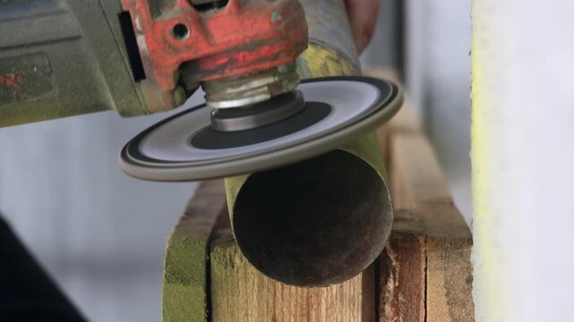 Macro shot of grinding power tool removing yellow paint and rust from steel tube
