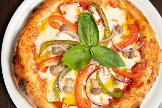 Pizza avec des l&eacute;gumes et de la viande sur une assiette blanche