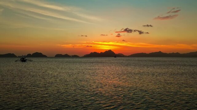 Aerial Time Lapse Forward Tracking Shot Toward Sunset at Corong Corong Beach in El Nido, Philippines. Drone Hyperlapse View of Moving Clouds, Fiery Dusk Sky, and Calm Sea.