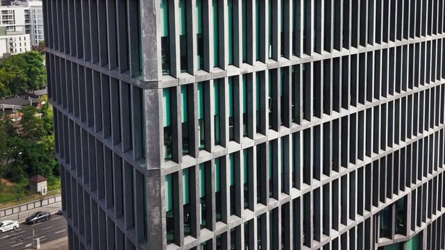 Modern office building skyscraper glass facade business tower corporate real estate architecture. A close up architectural perspective highlights the geometric lines and repetitive concrete grid