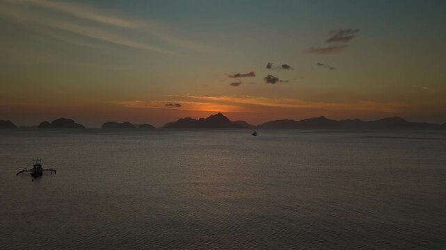 Aerial Rocket Shot Over Corong Corong Beach at Sunset in El Nido, Philippines. Cinematic Drone Vertical Ascent and Reveal of Orange Dusk Sky and Limestone Karst Islands.