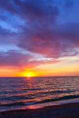Obraz premium Colorful sunset sea dramatic clouds reflecting vibrant orange, pink purple hues across calm water surface