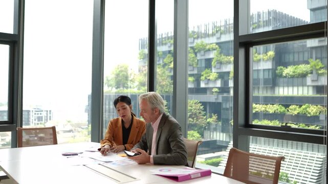 Female employee presents document to senior executive during meeting before leaving while experienced manager rejects proposal and continues discussion with another colleague in corporate workplace