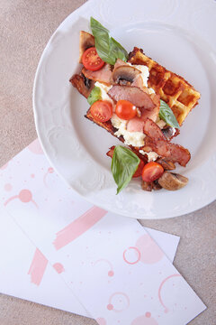 Viennese waffles with bacon, champignons and cherry tomatoes on potato pillow. Classic waffles with bacon. Delicious and nutritious breakfast. Concept of business breakfast. Top view