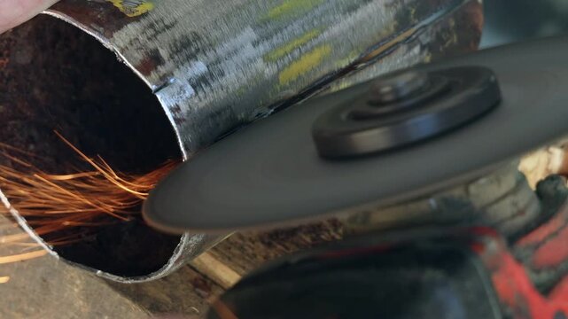 Selective focus on an electric grinder tool and rusty metal workpiece in a workshop