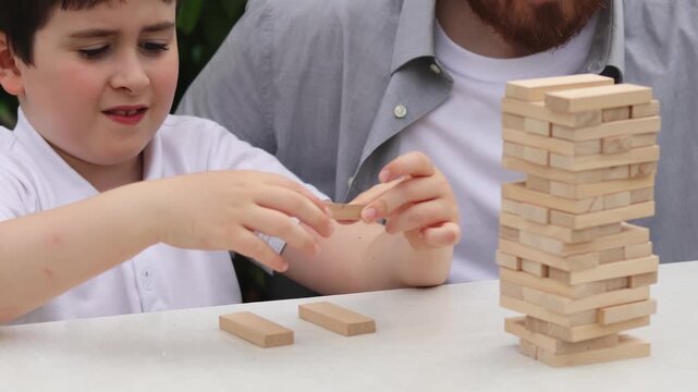 Jenga. Wooden blocks. Board game. Dad and son. Slow motion video. High quality 4k footage