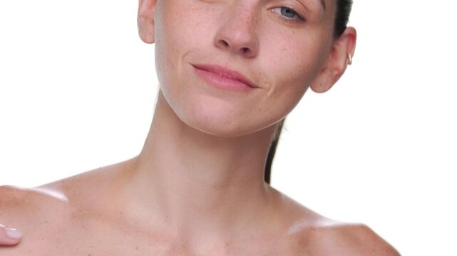 BCU shot of fair-skinned beauty model with freckles strokes her clavicles revealing nourished skin isolated on white | Nourished skin concept for body wash commercial